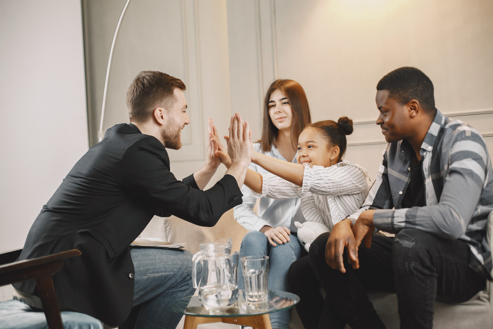 Child Inclusive Mediation Sydney—man and three kids indoors, sharing a joyful high five in a supportive setting.