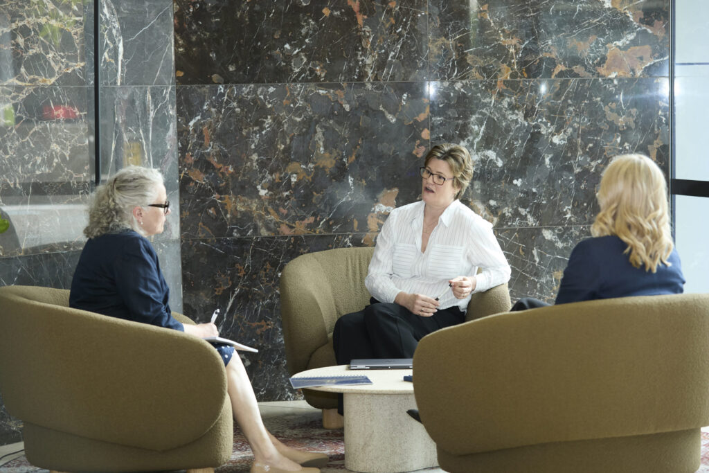 Three women from the Kannen mediation team discuss Child Inclusive Mediation Sydney in a marble-walled office lobby.