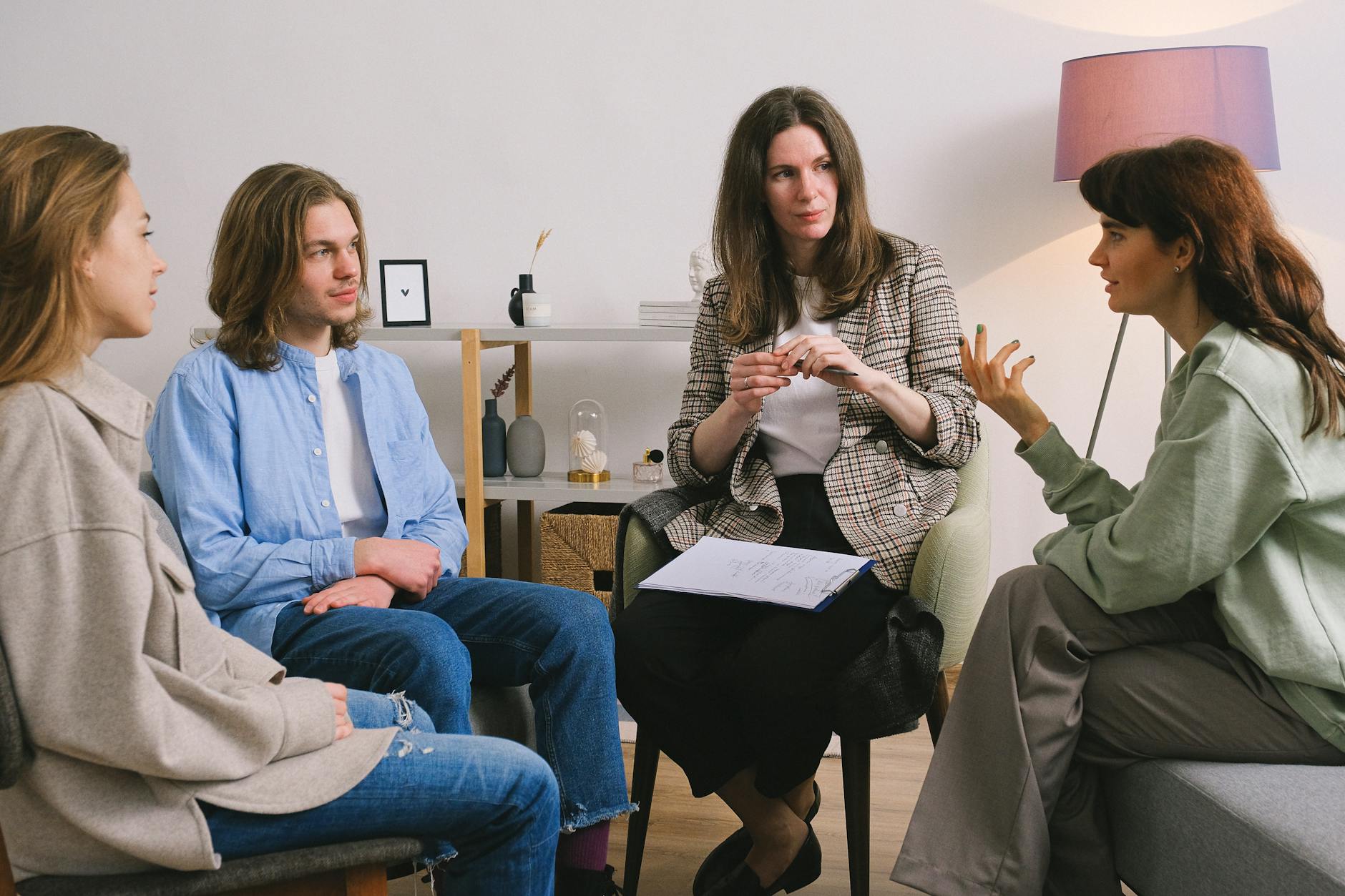 Four people discuss an agreement in a bright, minimalist office, with one taking notes on a clipboard.